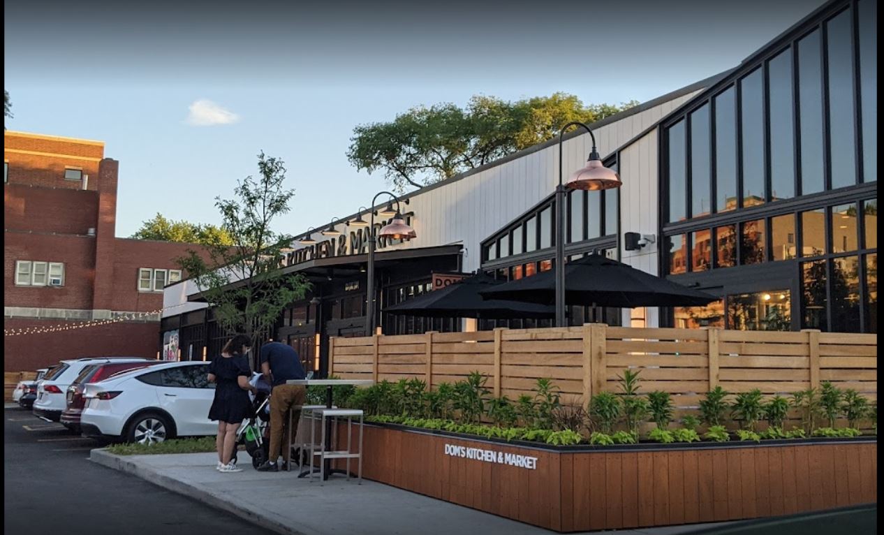 dom's kitchen market exterior with fenced off patio and umbrellas