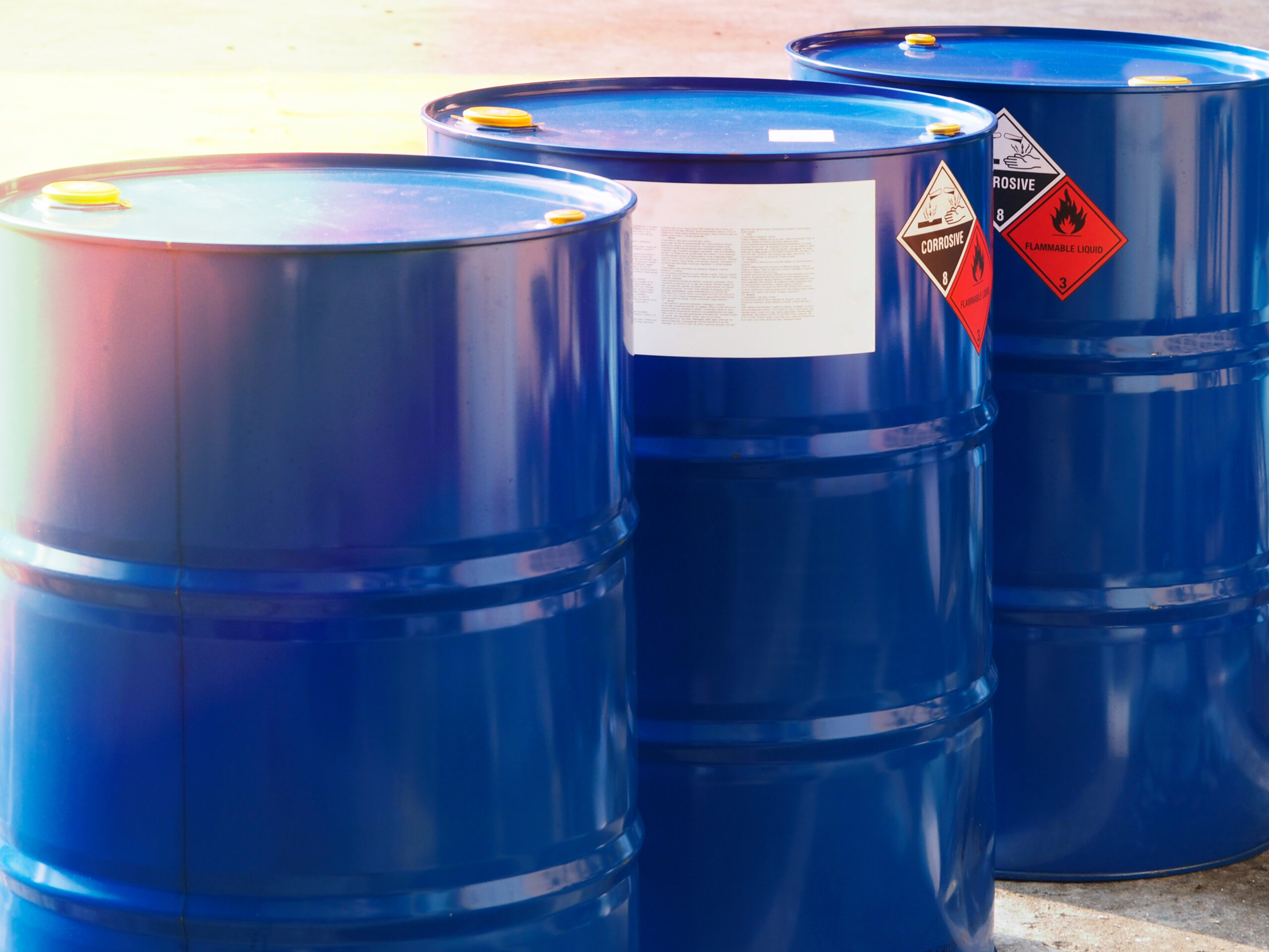 three blue barrels that include corrosive and flammable liquid