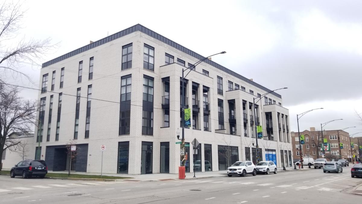 street view of a white-bricked multi-use building on a city block