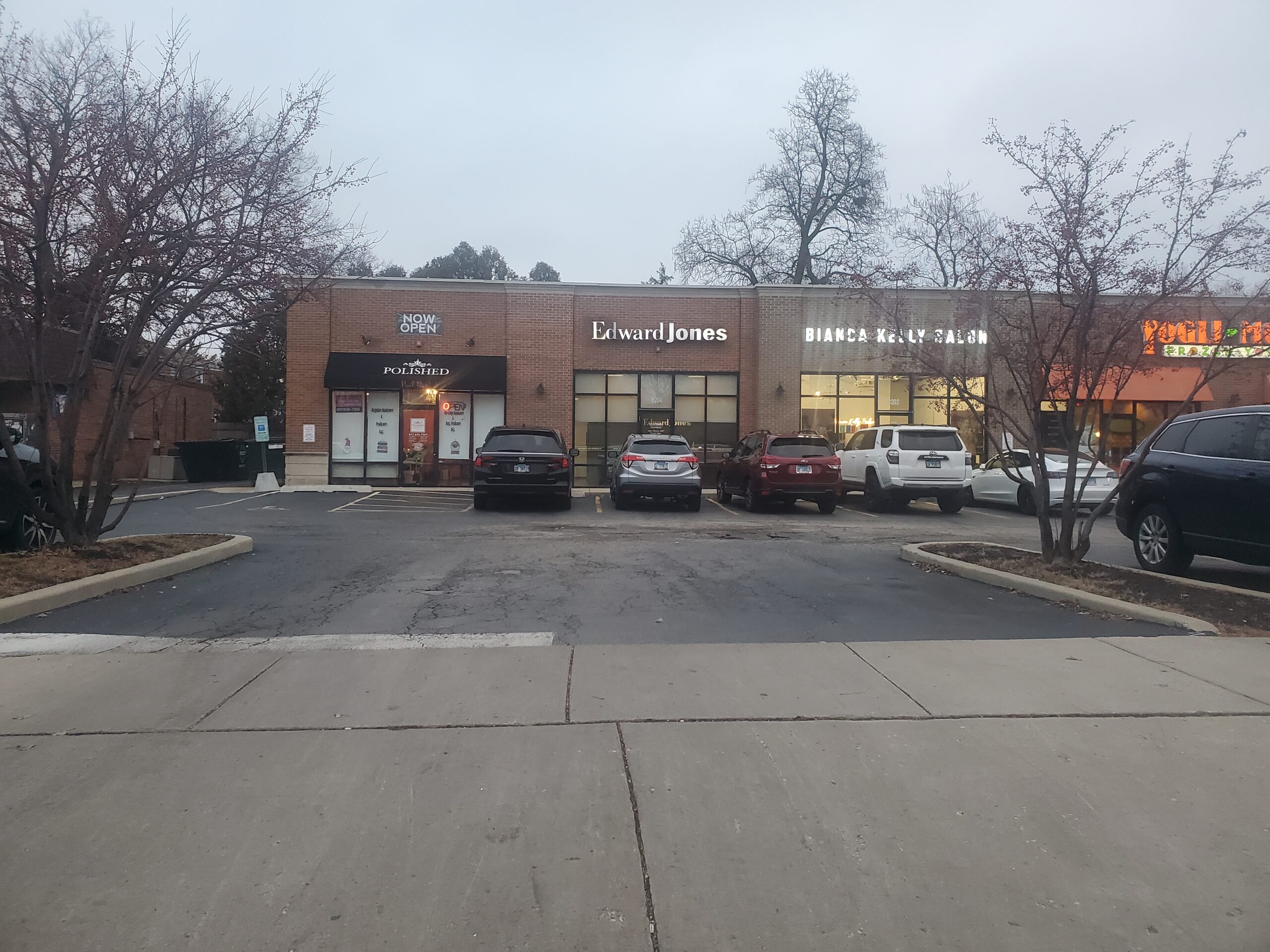 a separate entrance to the AK plaza with views of the uneven and pot-holes in the parking lot and driveway