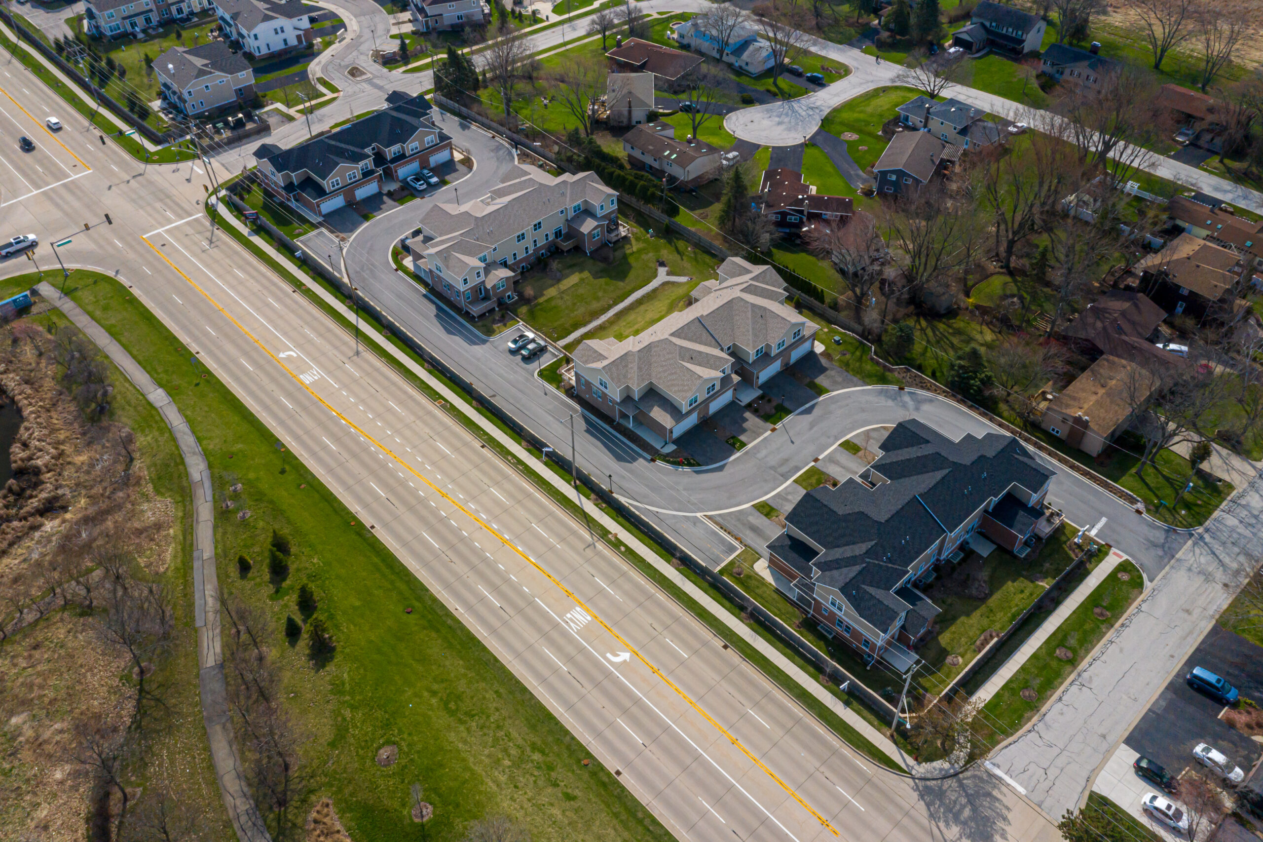 higher aerial view of Newberry Lane condo community that includes 4-lane highway, green spaces, and walking paths