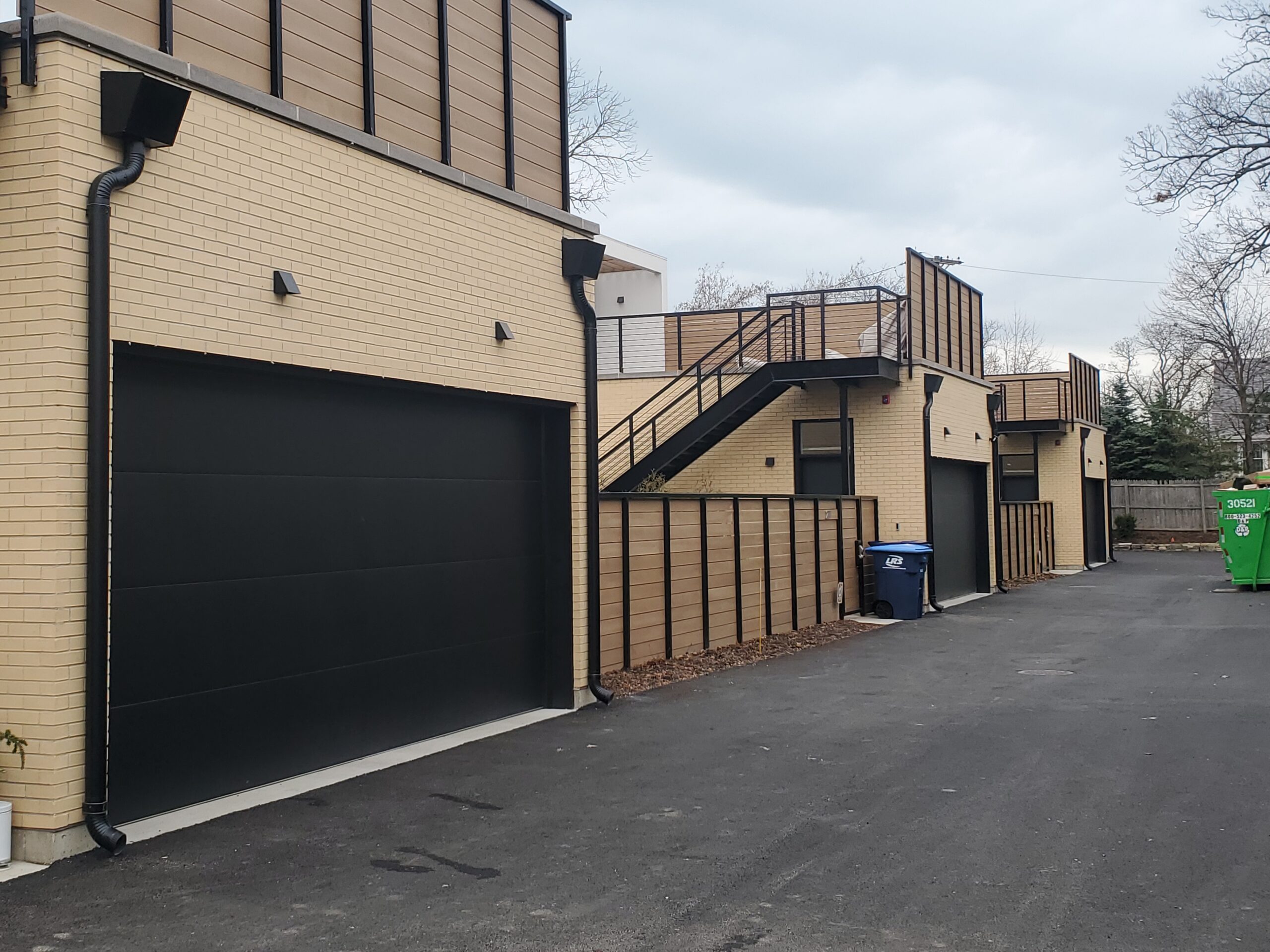 back alley view of St Johns Highland Park apartments that shows tan brick exterior and garage door entrances