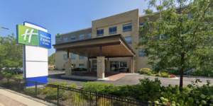 Exterior of a Holiday Inn Express & Suites with a covered porte-cochère and landscaped entrance.